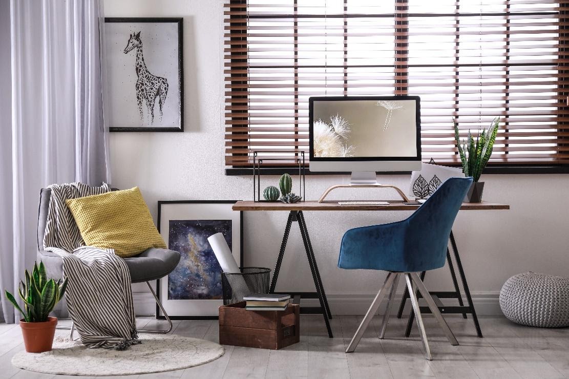 Comfortable workplace near window with horizontal faux wooden blinds in room